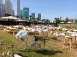 Outdoor event setup with picnic benches, umbrellas, decor, cocktail tables, and crate furniture