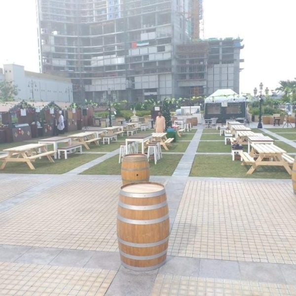 Rustic Wooden Barrel Cocktail Table setup with picnic benches, barstools, and high tables for a stylish outdoor event.